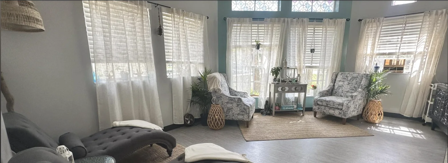 The Synergy Massage lobby: teal walls, stained glass, sheer curtains, armchairs in sunlight